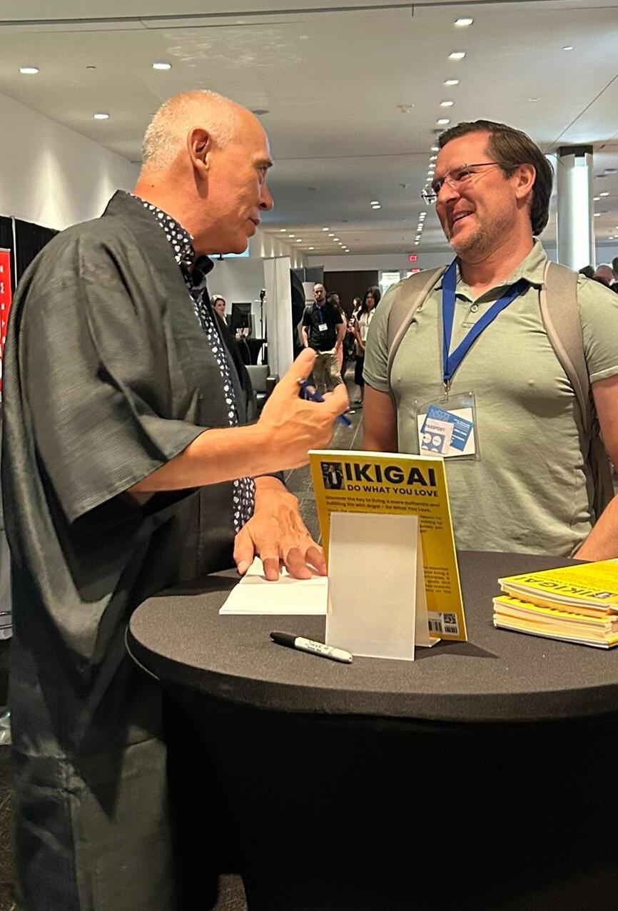 Tim Tamashiro chatting with an attendee during a book signing event, sharing a moment of connection after his ikigai keynote.